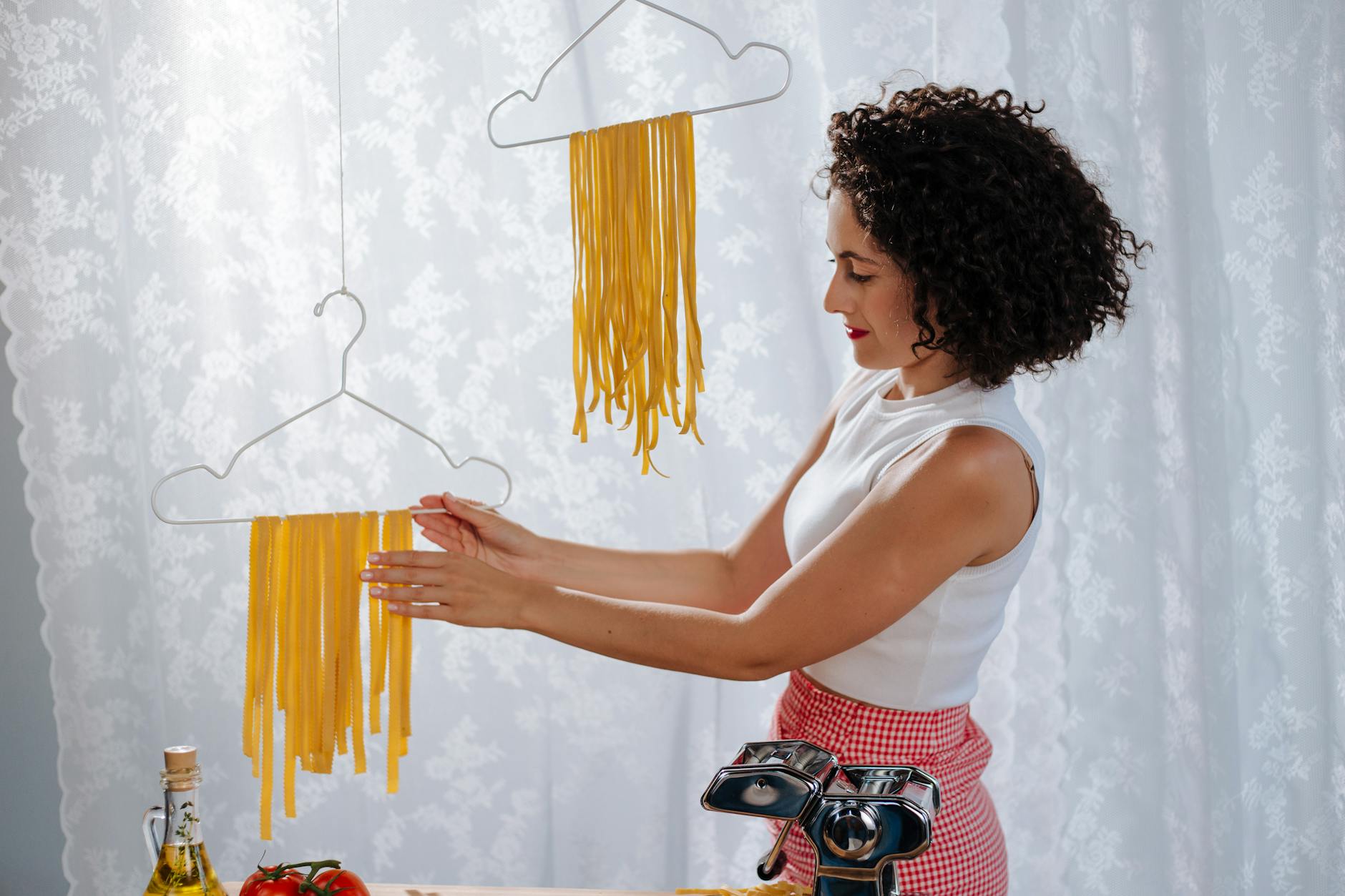 a female touching clothing hanger with drying pasta