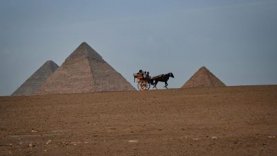 people riding a horse carriage by the pyramids giza egypt