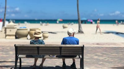 man and woman sitting on brown wooden bench