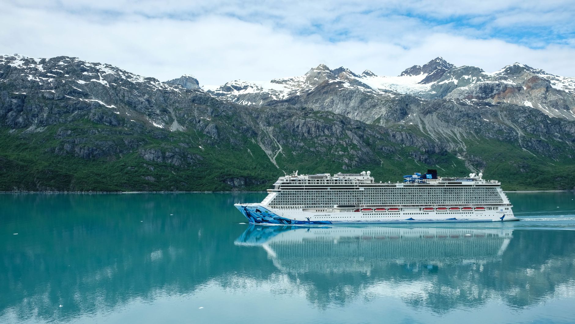 a cruise ship sailing on sea near the snow covered mountain