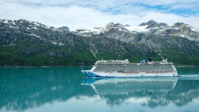 a cruise ship sailing on sea near the snow covered mountain