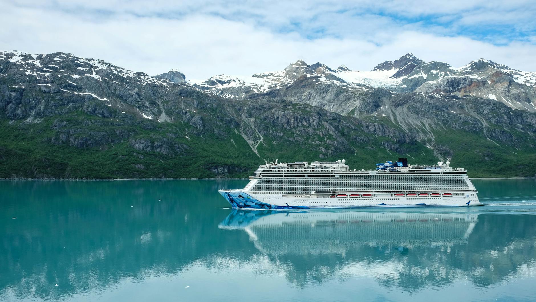 a cruise ship sailing on sea near the snow covered mountain