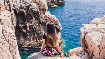 woman sitting at edge of rock
