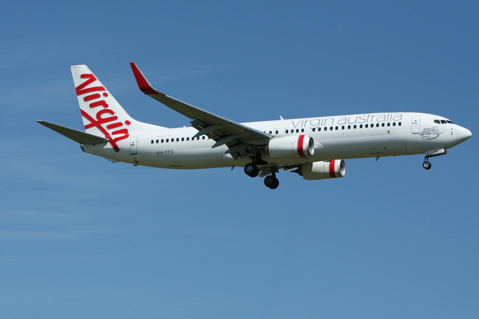 white and red virgin australia airplane mid air under blue and white sky during daytime