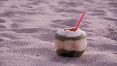 a coconut with straw on the sand