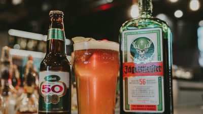 a drinking glass between glass bottles