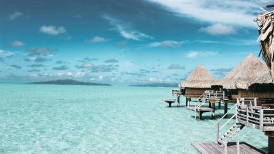 three brown wooden cottage and sea