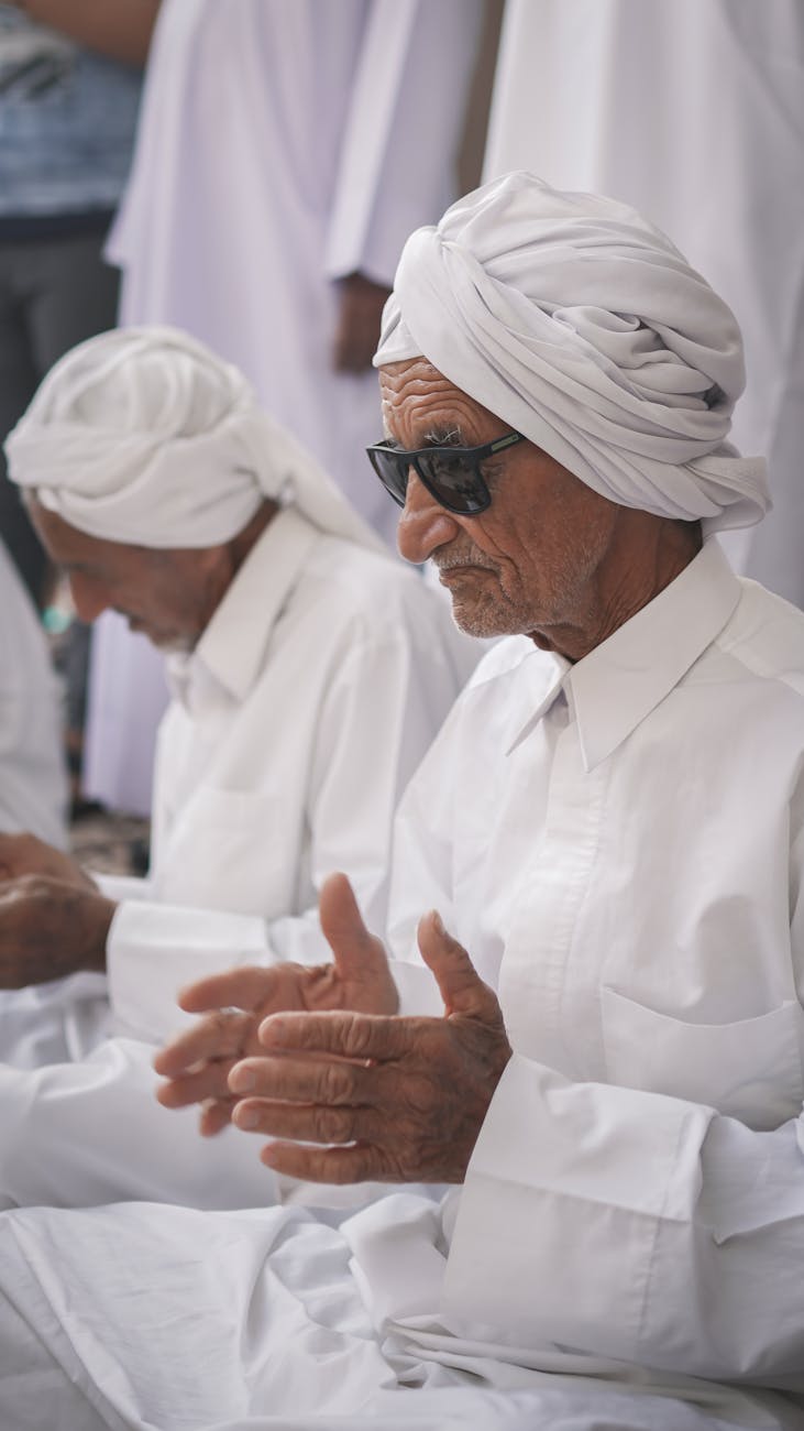 elderly man in a white shirt and turban clapping to the beat at a festival