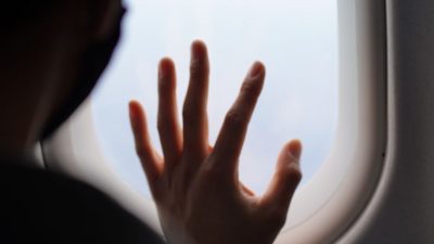 person holding hand against plane window