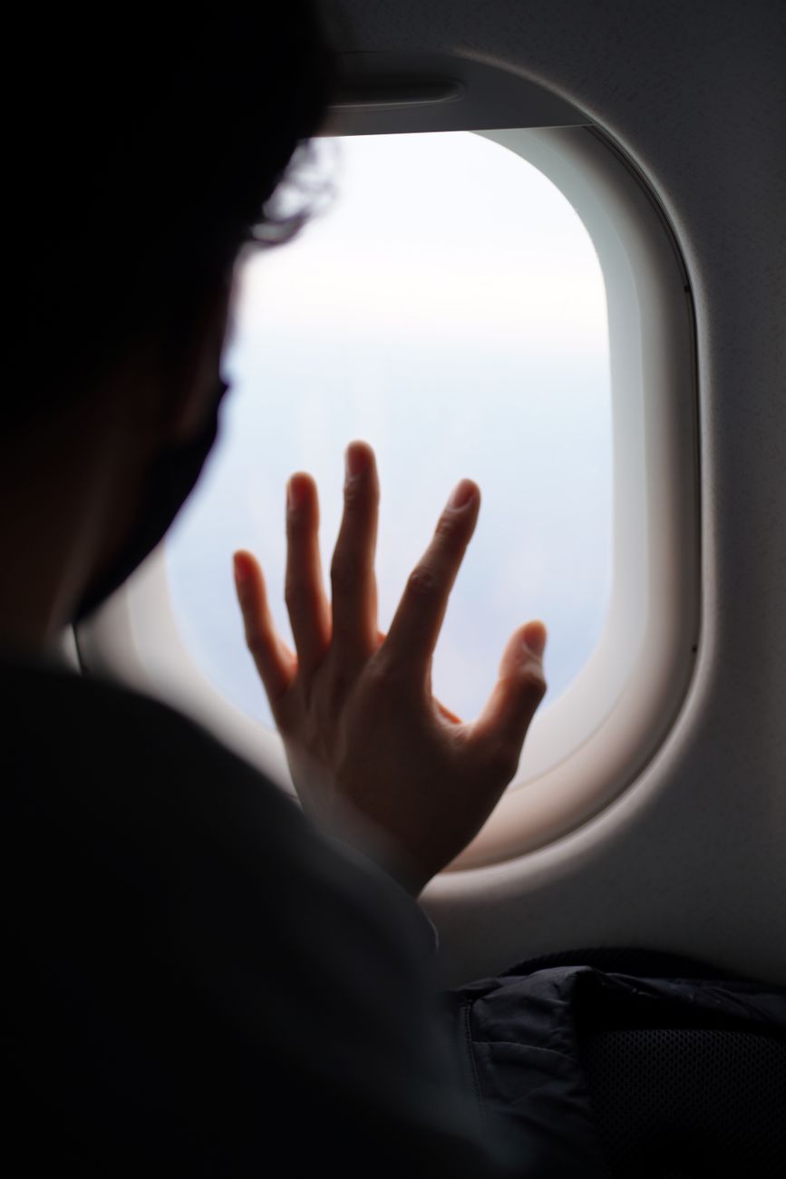 person holding hand against plane window