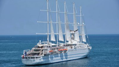 cruise ship with sails sailing under a blue sky