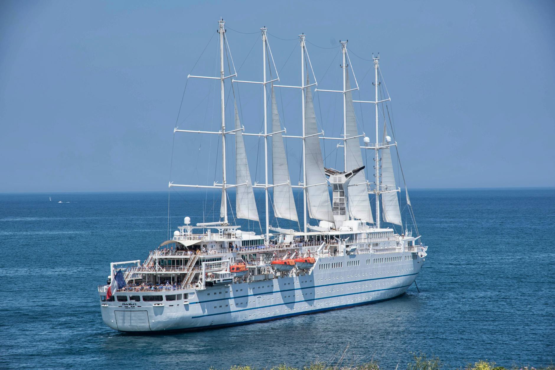 cruise ship with sails sailing under a blue sky