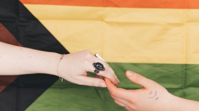 hands touching against progress pride flag