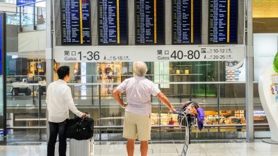 people looking at departure board at an airport