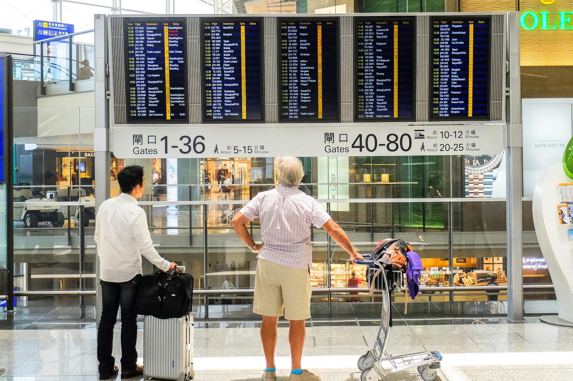 people looking at departure board at an airport