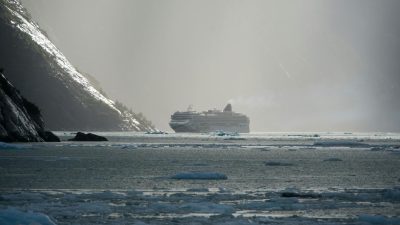white cruise ship near mountain slopes
