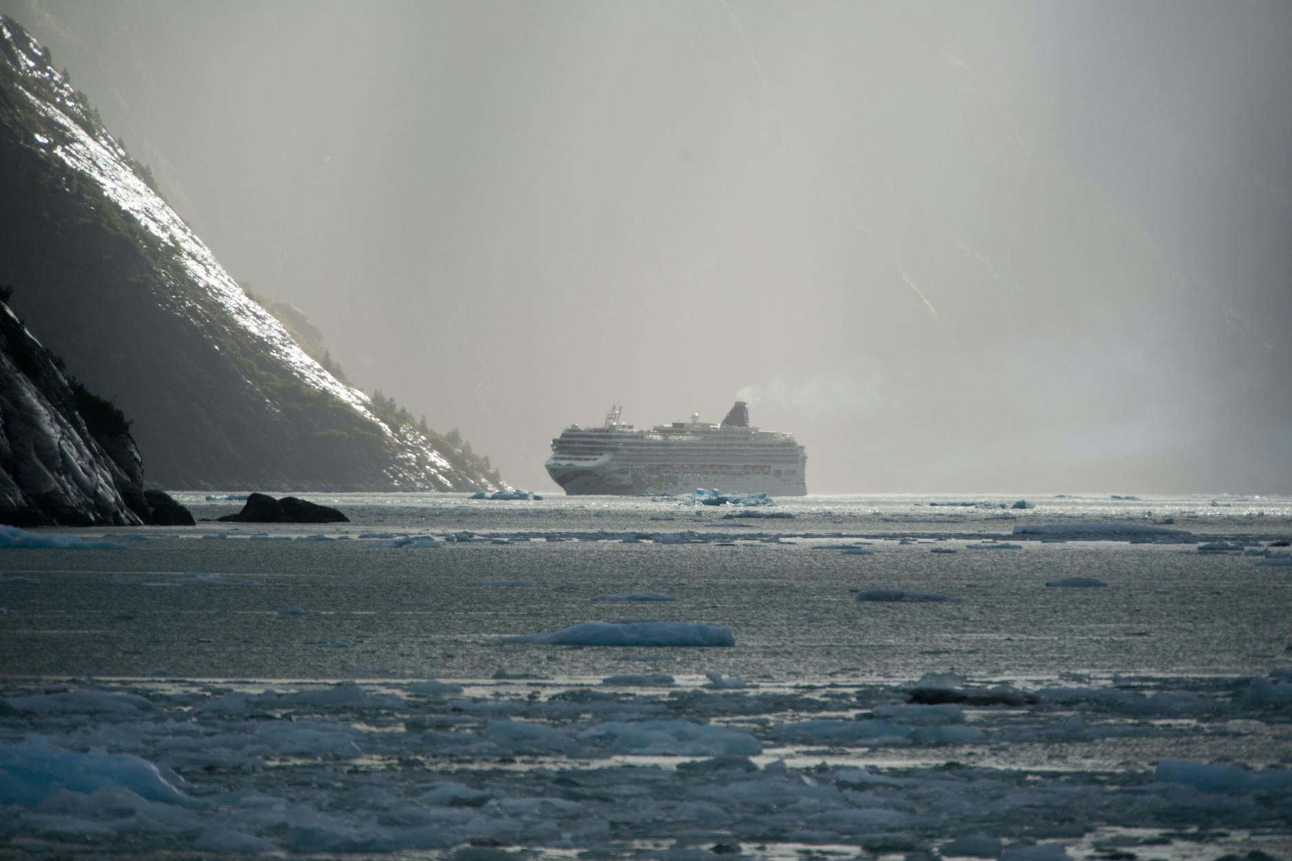 white cruise ship near mountain slopes