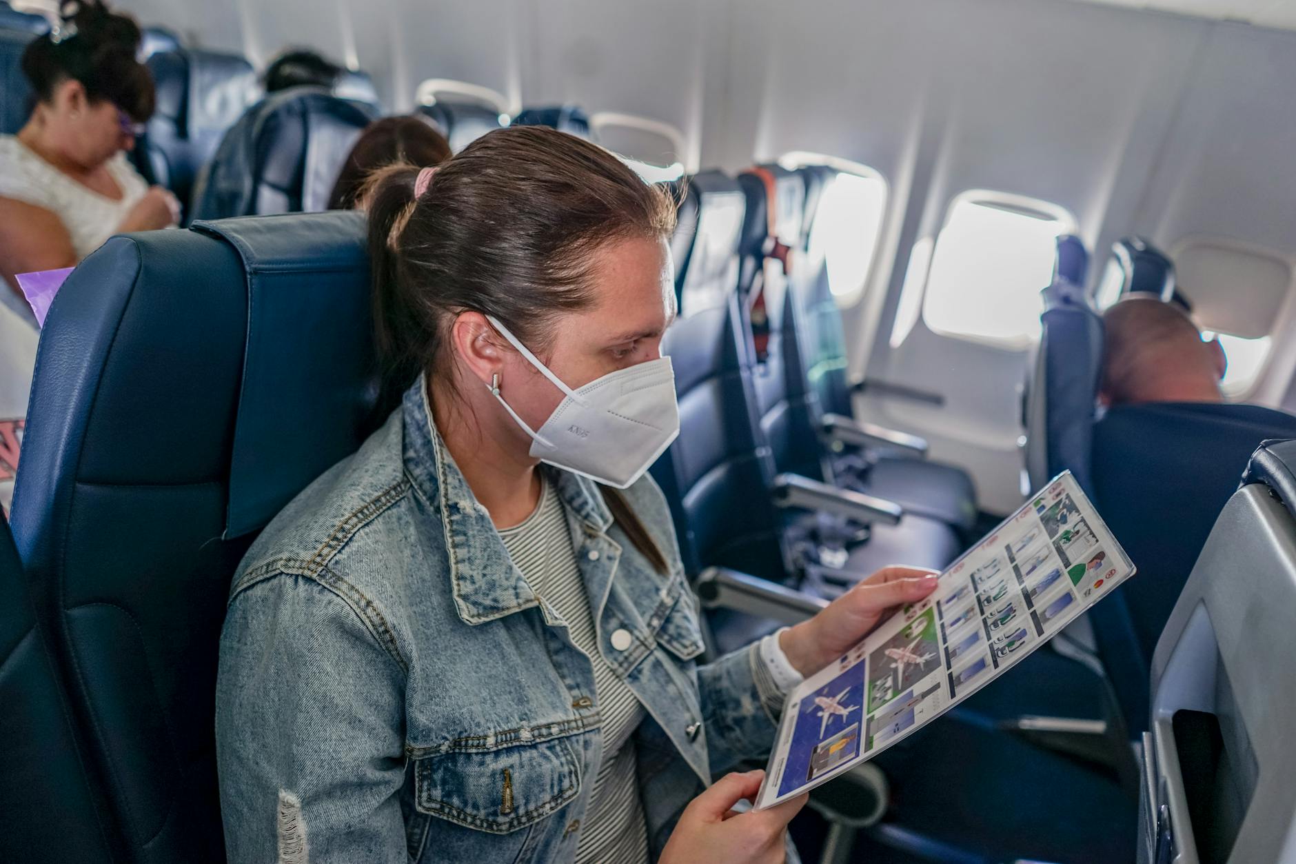 woman in denim jacket sitting inside the plane