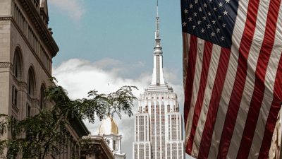 the american flag on a flag pole with the empire state building on the background