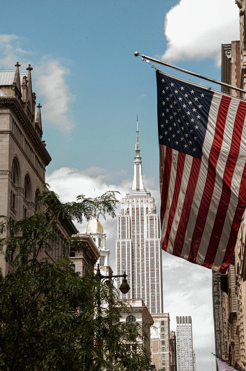the american flag on a flag pole with the empire state building on the background