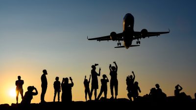 silhouettes of people photographing a plane at sunset