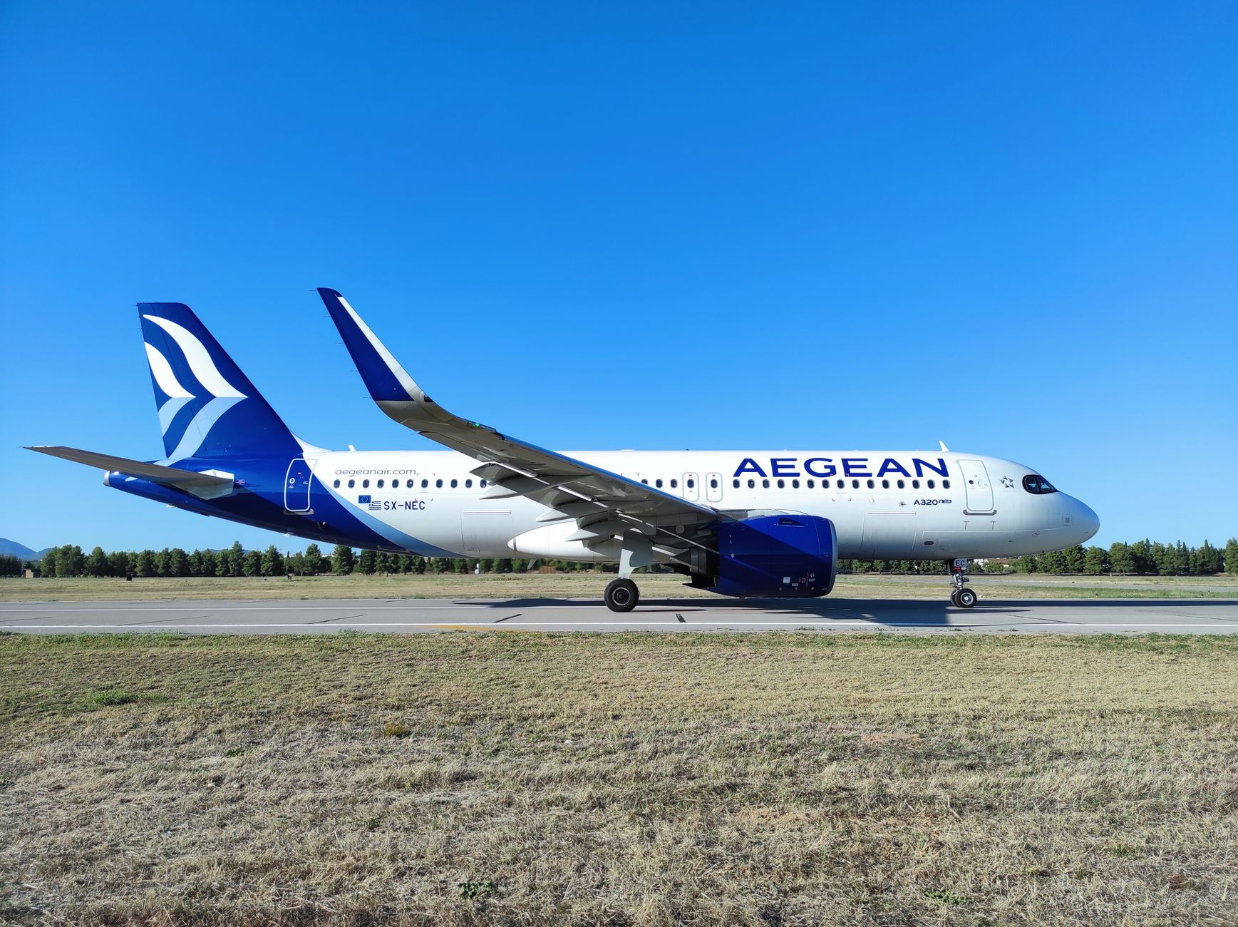 white airplane on a runway under blue sky