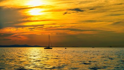 silhouette of boat on body of water during sunset