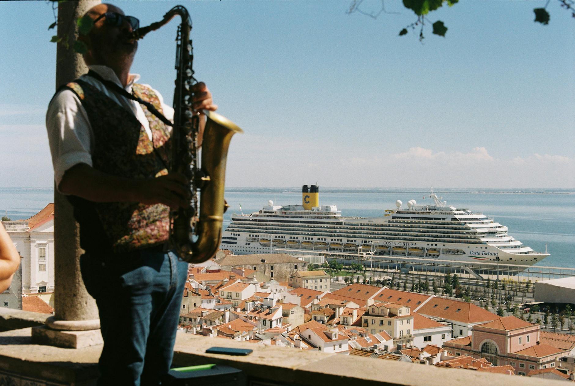 man playing on saxophone in front of town and ship on sea