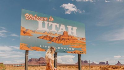 woman posing near welcome to utah advertisement