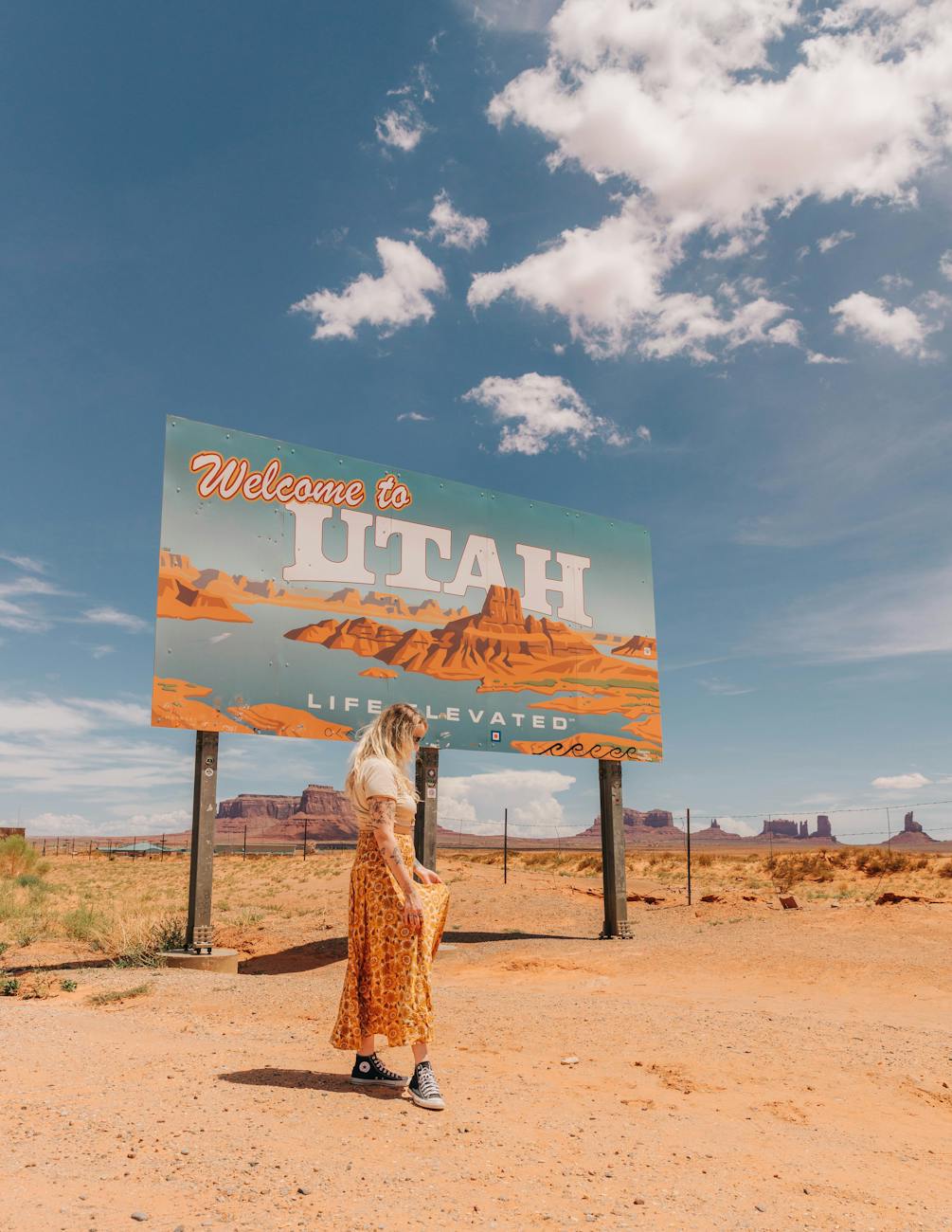 woman posing near welcome to utah advertisement