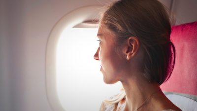 selective focus photo of woman sitting on chair looking outside window on plane
