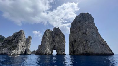 cloud on blue sky over rock formations on sea shore