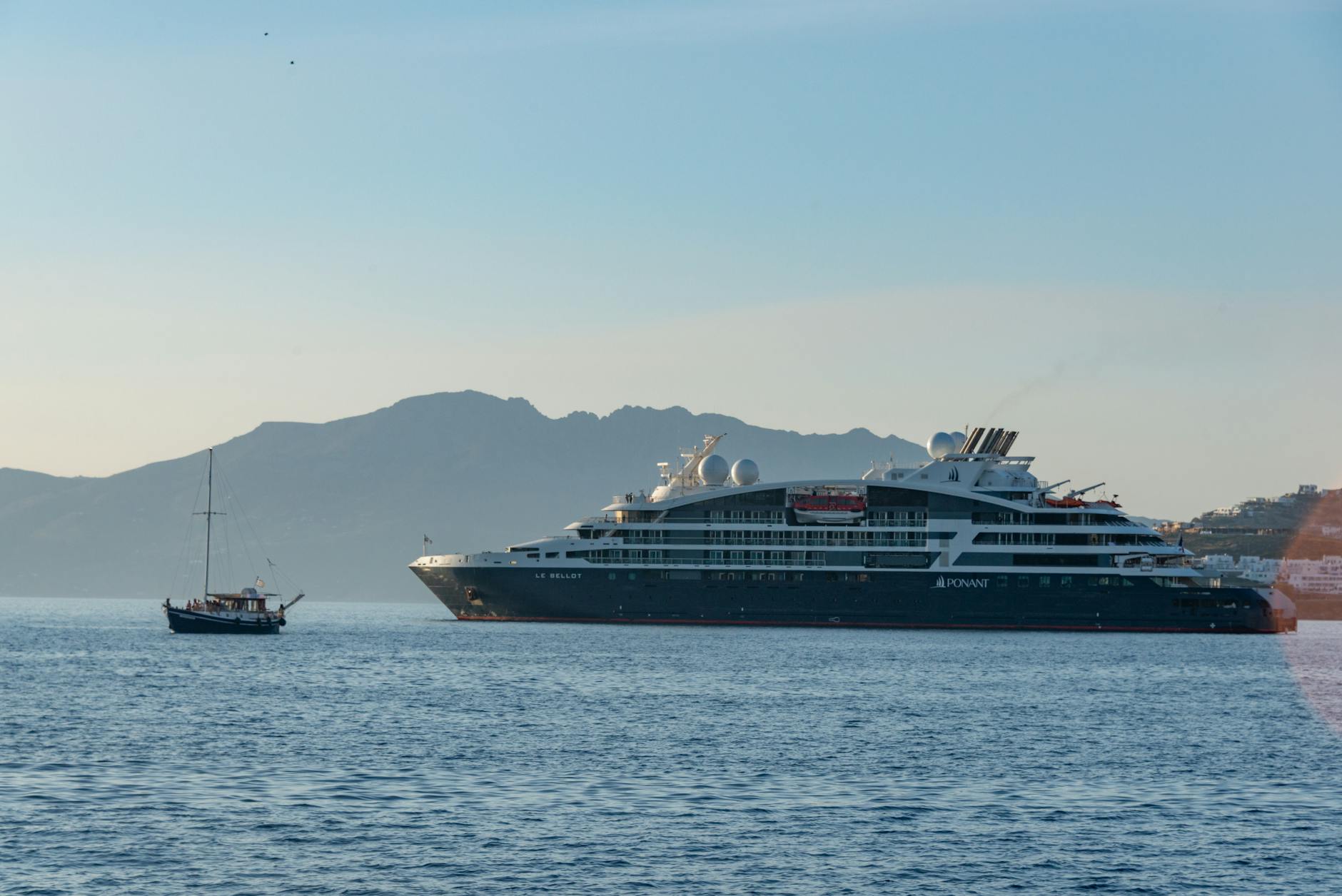 seascape with a large ferry and a small boat against a hill