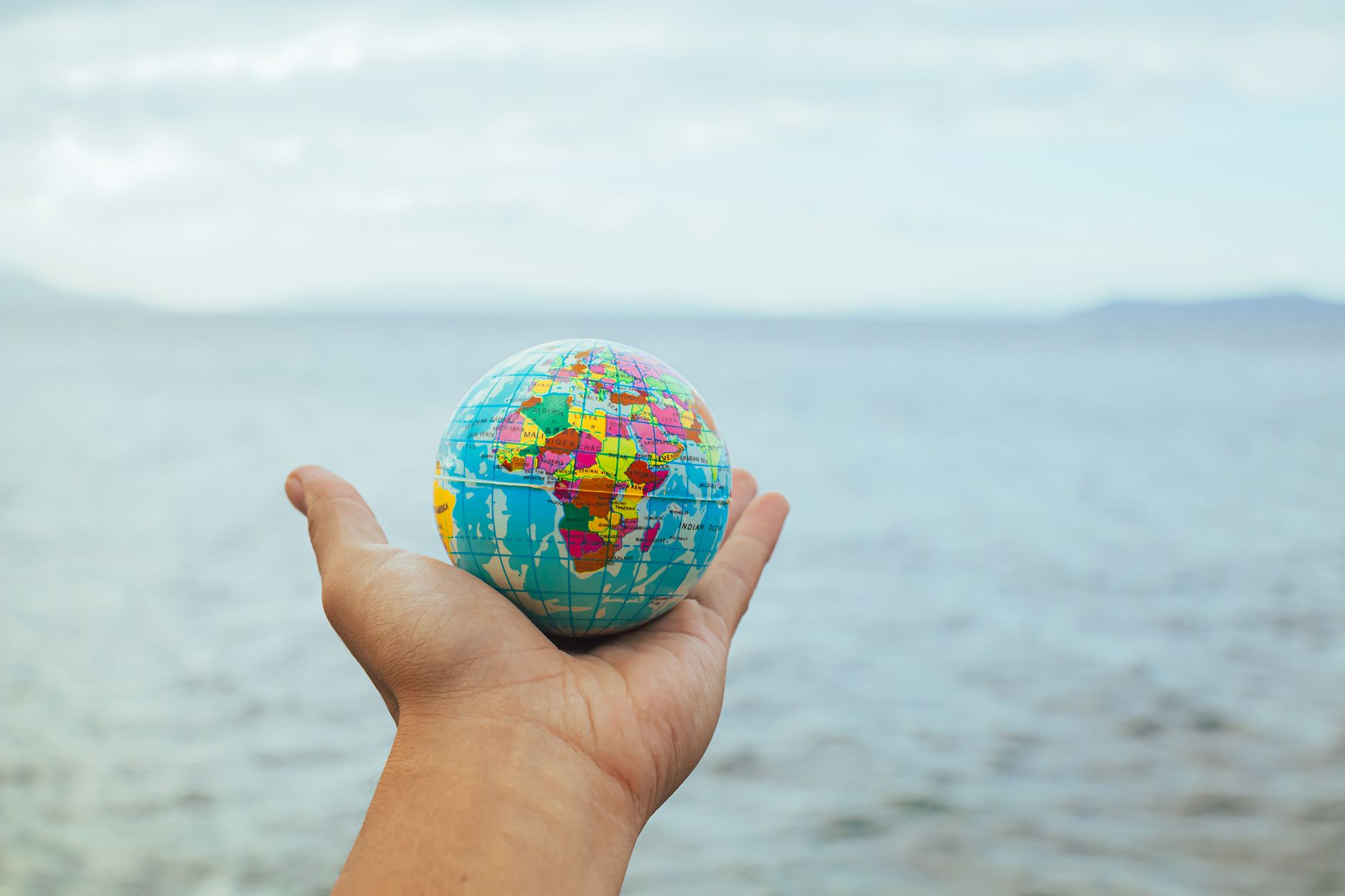 hand holding globe against sea