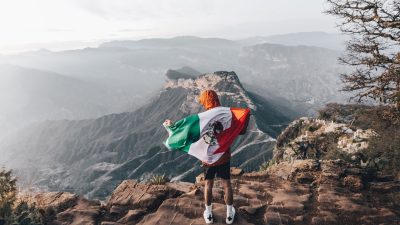 man standing with mexican flag in mountains