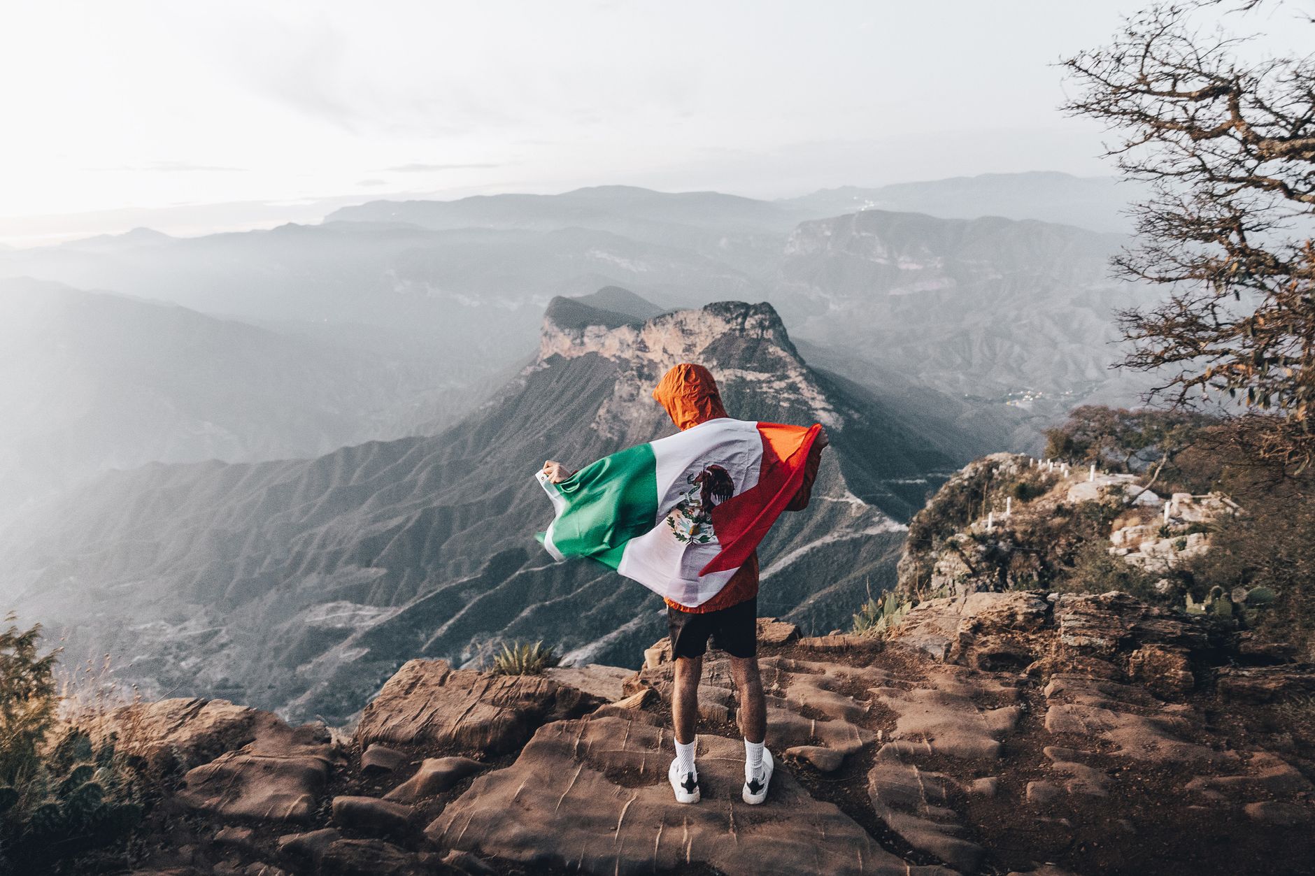 man standing with mexican flag in mountains