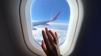 girl s hand on the porthole in the plane in flight