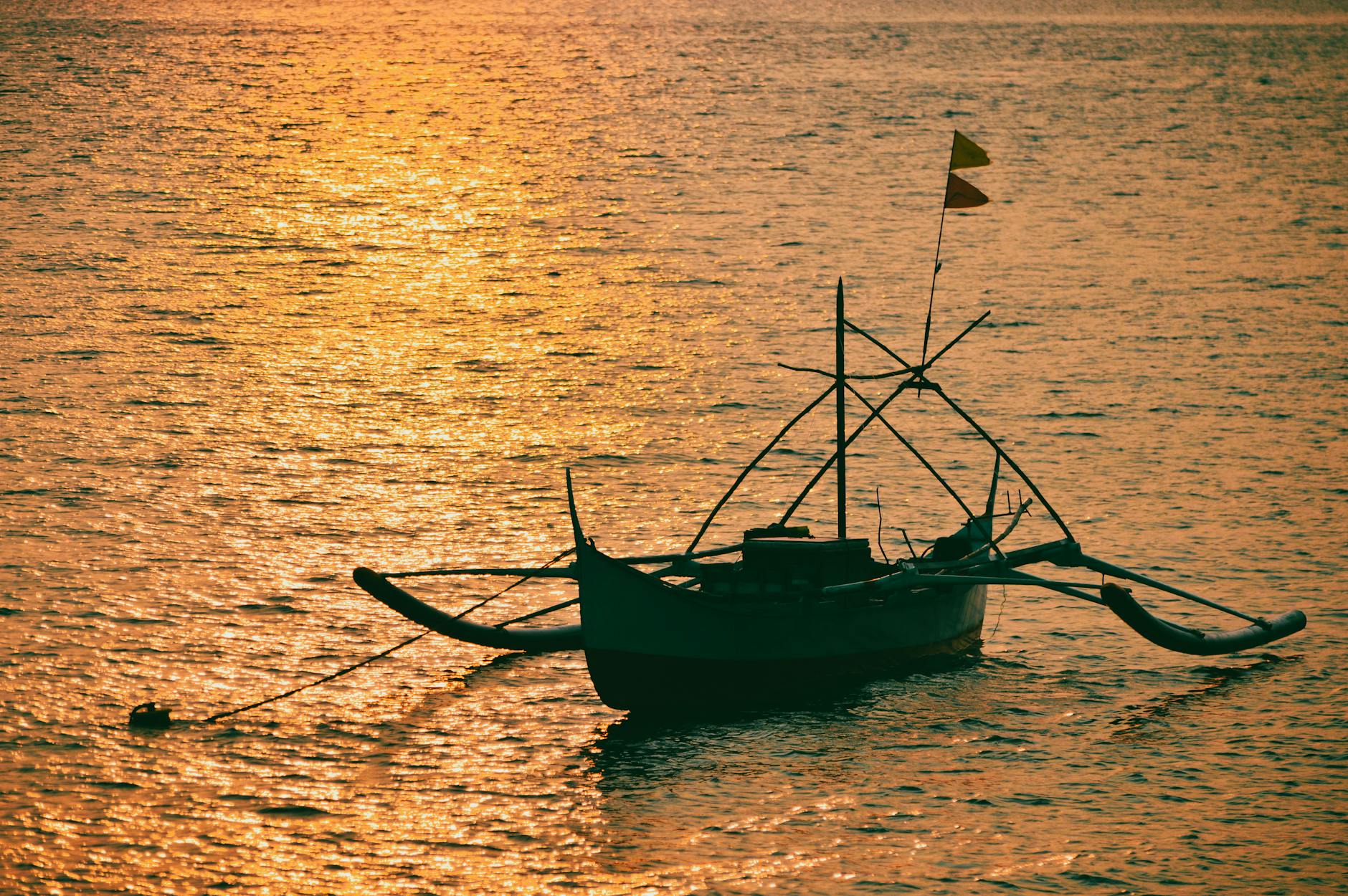 silhouette of boat sailing in water on sunset