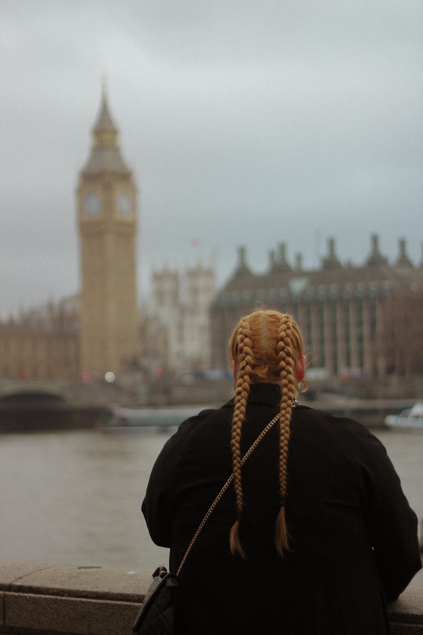back view of a woman standing on the thames bank and looking at big ben in london england