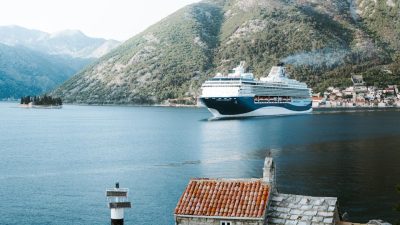 stone house on sea shore and cruise ship sailing behind