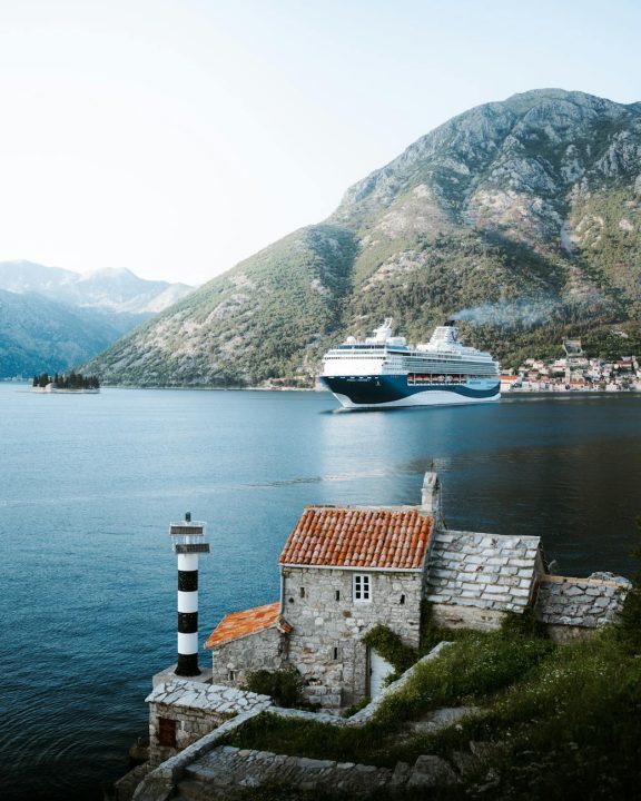stone house on sea shore and cruise ship sailing behind