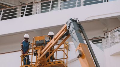 man working on scissor lift by passenger ship