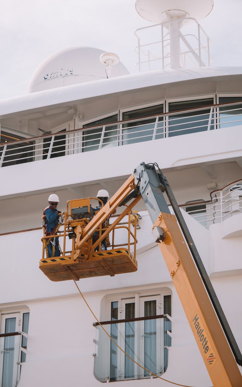 man working on scissor lift by passenger ship