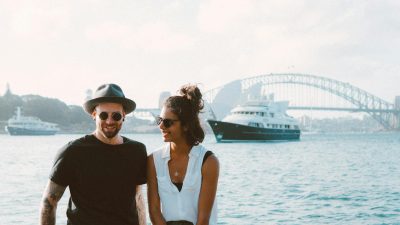man and woman sitting on bench beside body of water