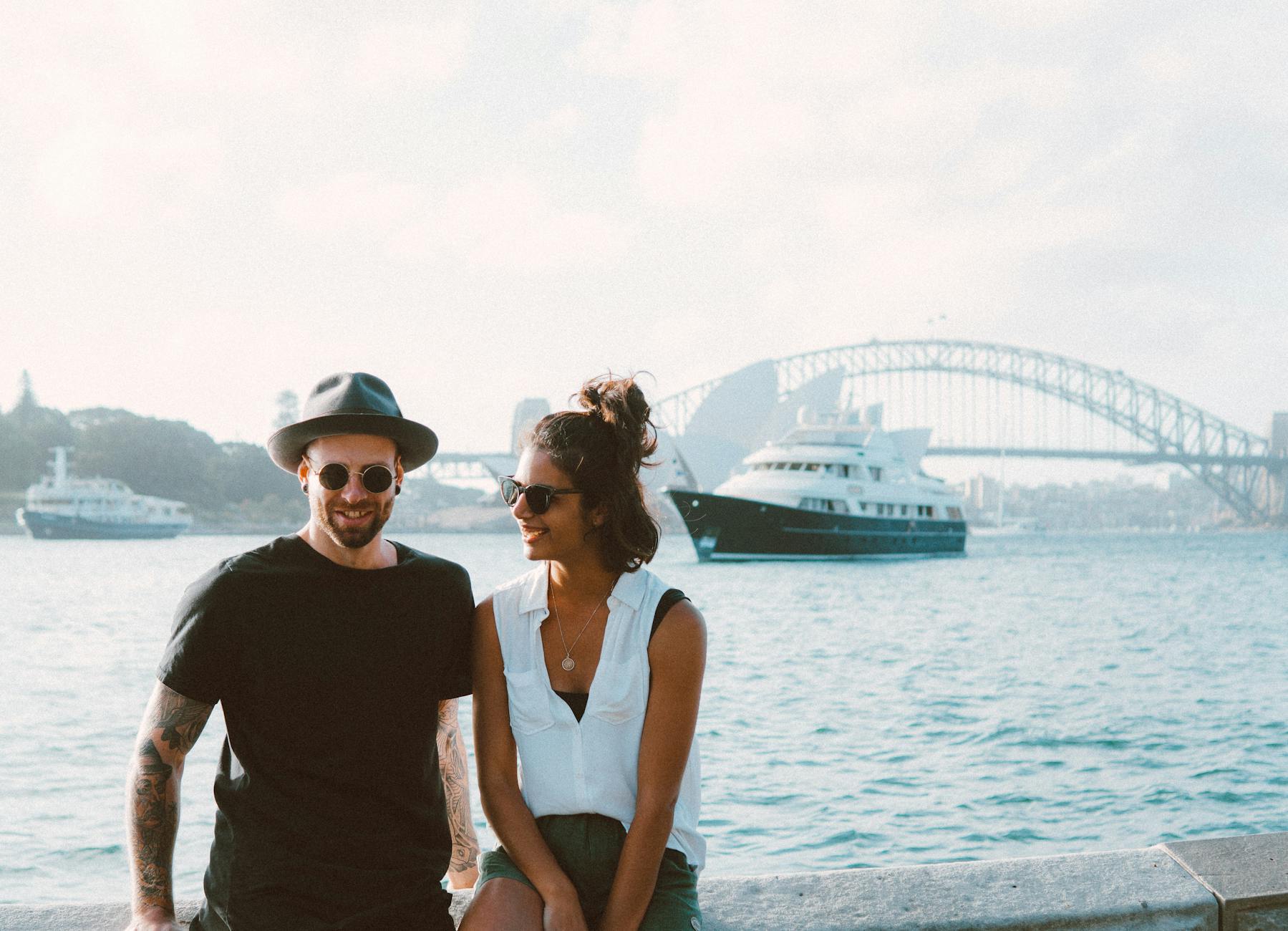man and woman sitting on bench beside body of water