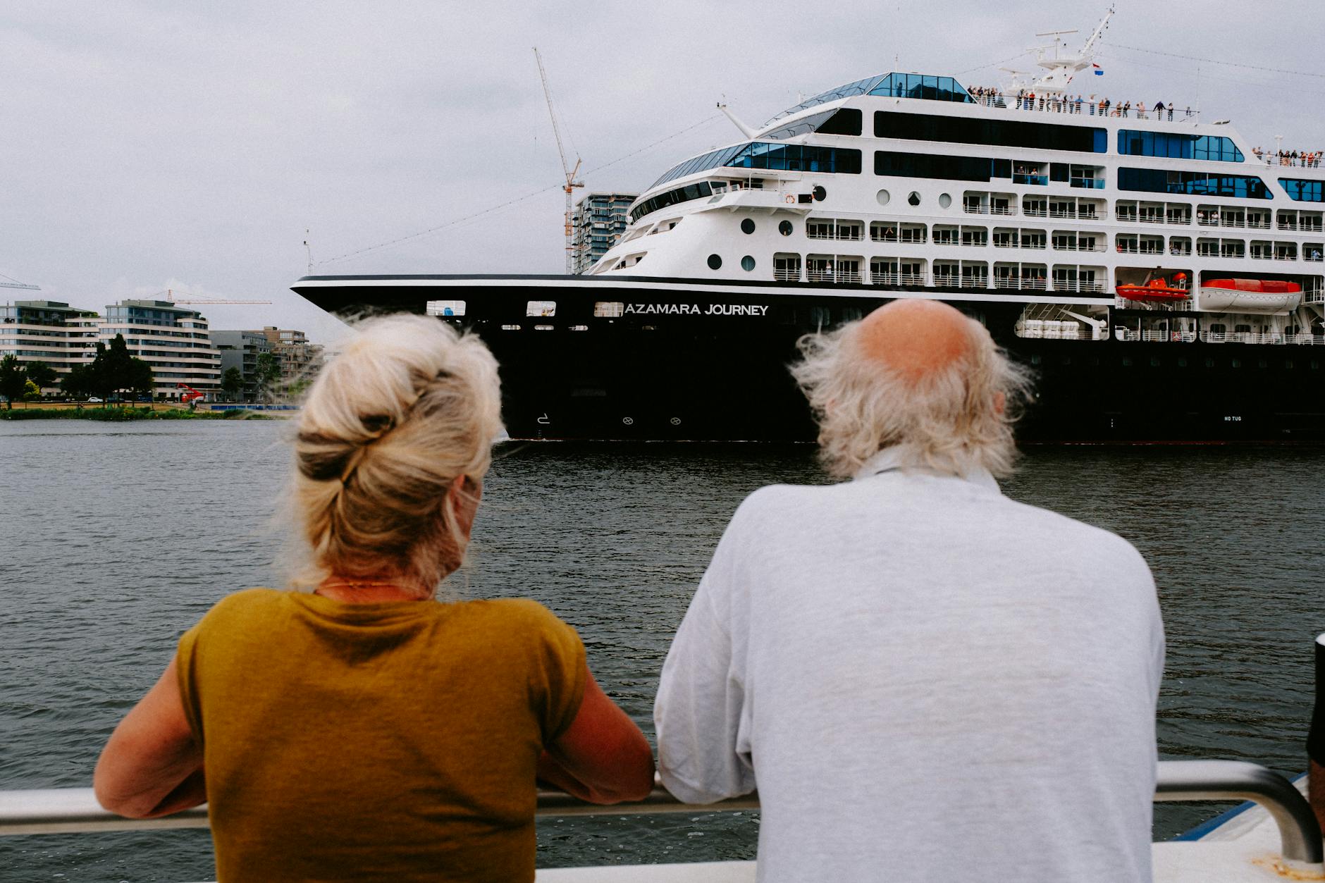 two people looking out at a cruise ship from a boat