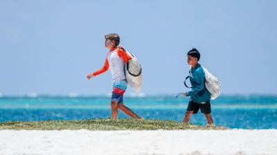 boys walking with bags on sea shore