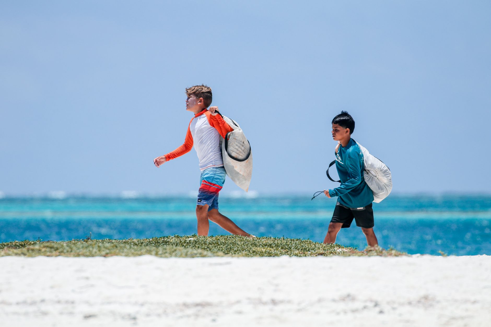 boys walking with bags on sea shore