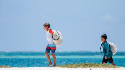 boys carrying bags on beach
