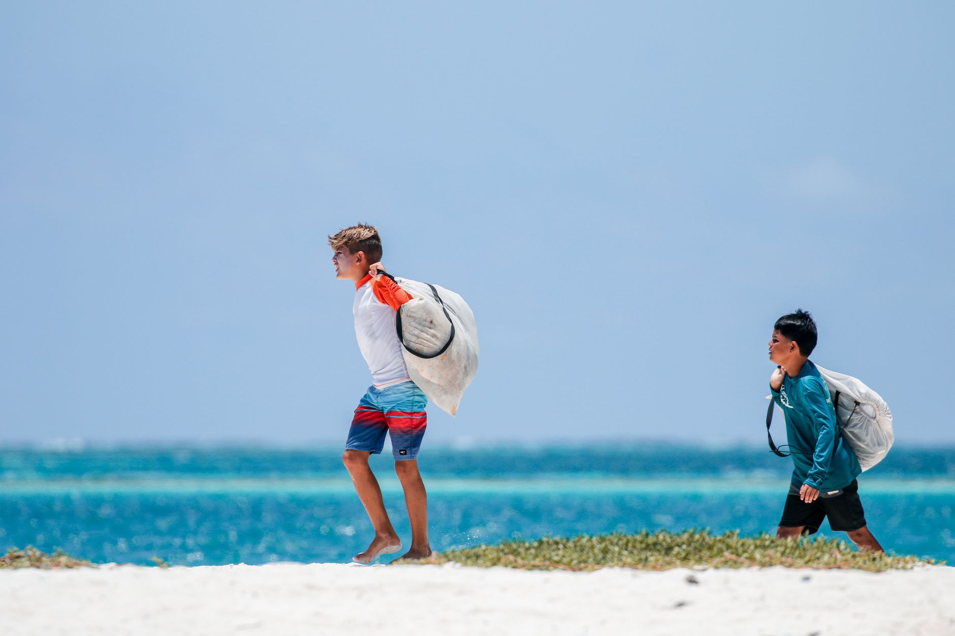 boys carrying bags on beach